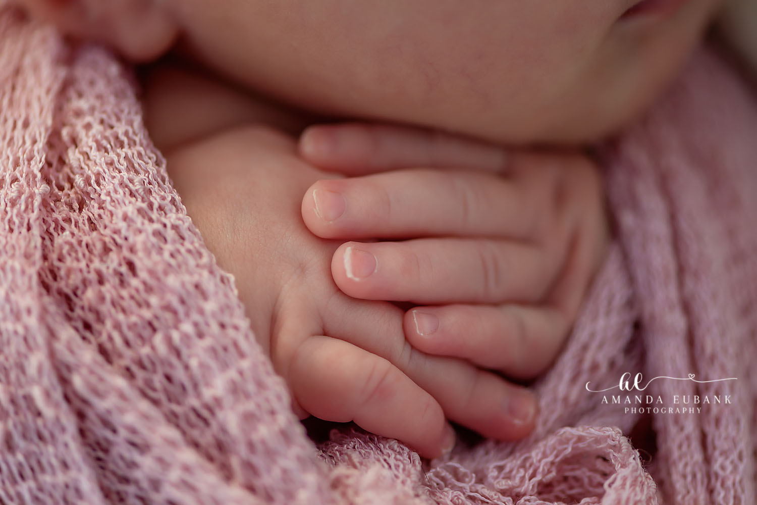 Close-up detail of a newborn baby’s tiny hands resting on a soft pink knit wrap, photographed by a Santa Rosa Beach newborn photographer