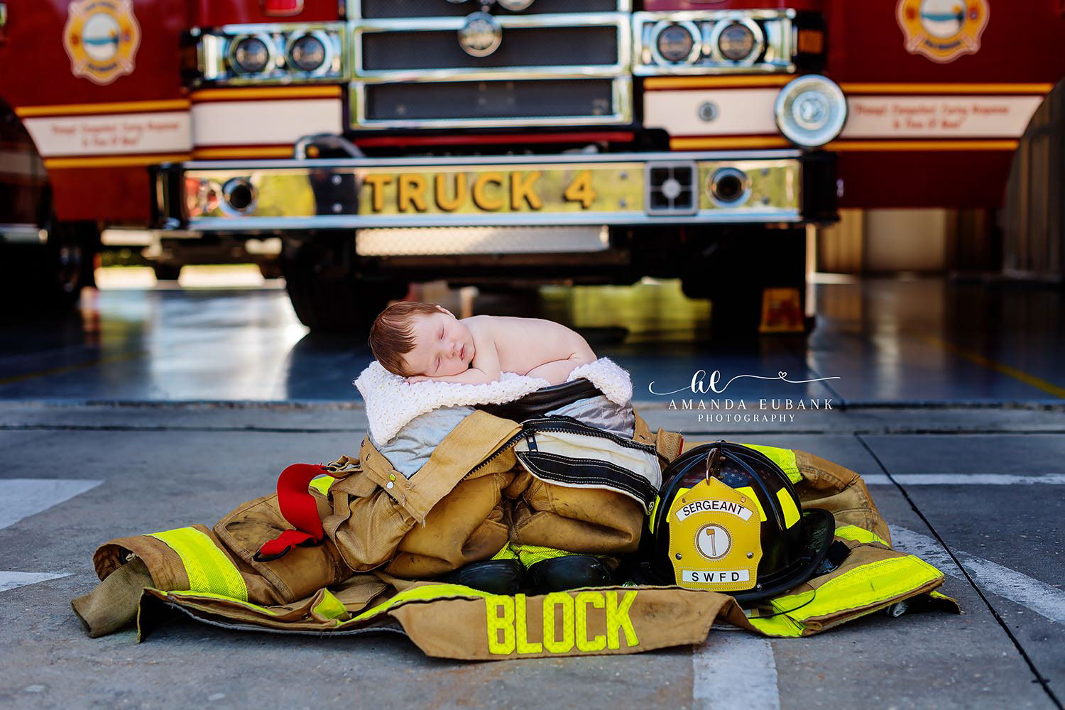 Santa Rosa Beach Photographer Newborn baby sleeping on firefighter gear in front of a fire truck, a themed newborn session taken by a Santa Rosa Beach newborn photographer