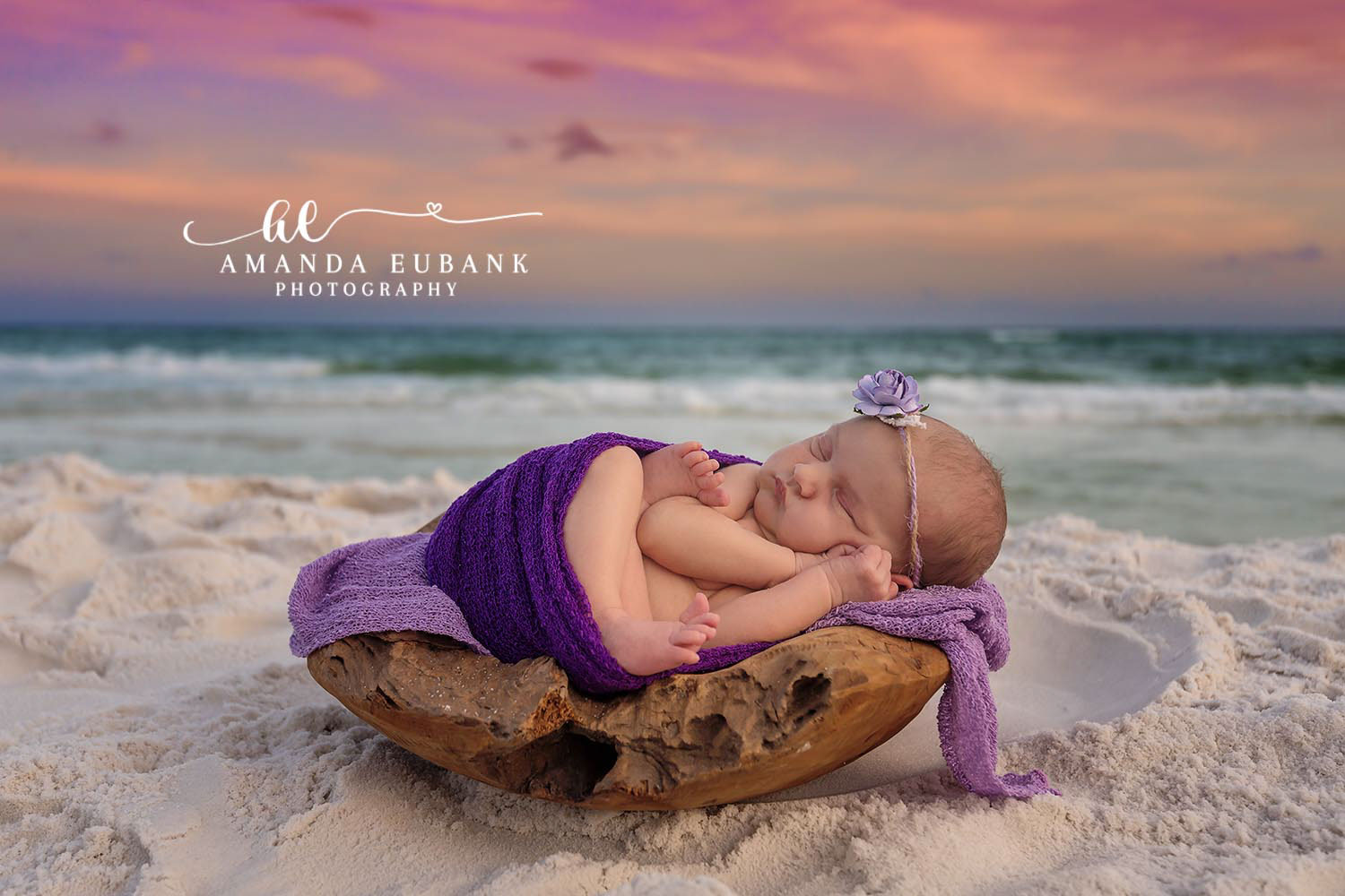 Santa Rosa Beach Newborn Photographer – Sunset Beach Newborn Portrait Newborn baby wrapped in a purple swaddle sleeping in a wooden bowl on the beach at sunset, taken by a Santa Rosa Beach newborn photographer