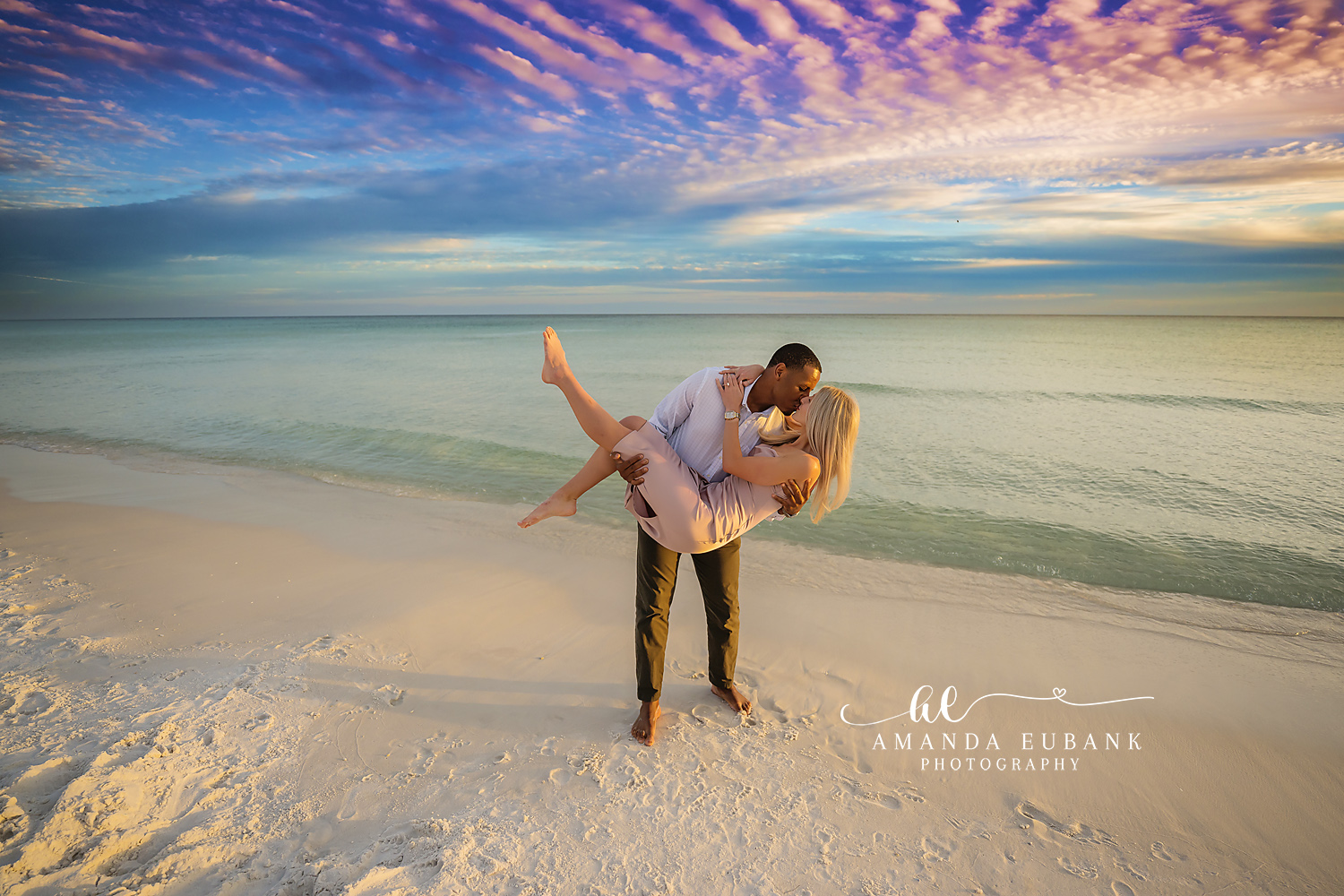 Santa Rosa Beach Engagement Photographer – Romantic Dip Kiss on the Beach Couple sharing a romantic dip kiss on the beach as the man cradles his partner near the shoreline, photographed by a Santa Rosa Beach engagement photographer