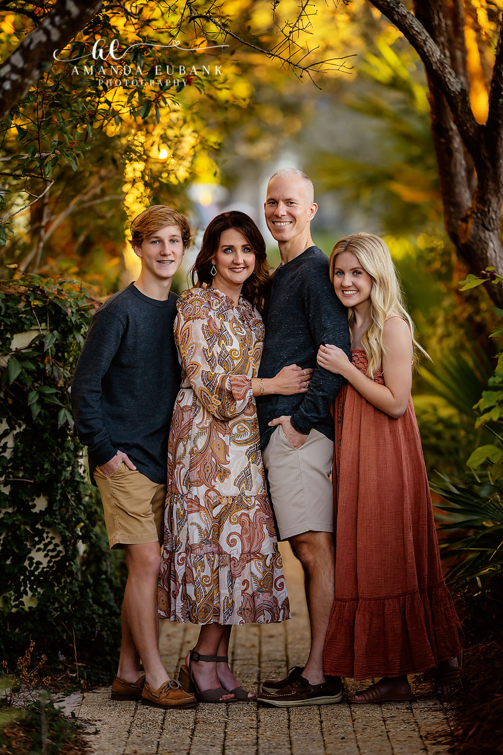 Santa Rosa Beach Family Photographer – Golden Hour Family Portrait in Autumn Close family of four with teenage children posing together among golden autumn foliage at golden hour, photographed by a Santa Rosa Beach family photographer