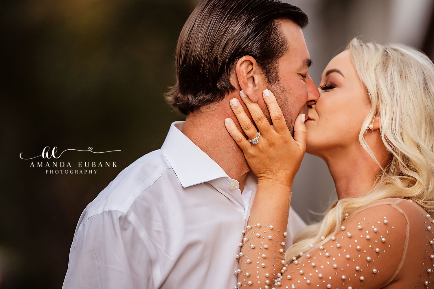 Intimate close-up of an engaged couple kissing as the woman rests her hand on his cheek, showing off her engagement ring and pearl-beaded gown, photographed by a Santa Rosa Beach engagement photographer