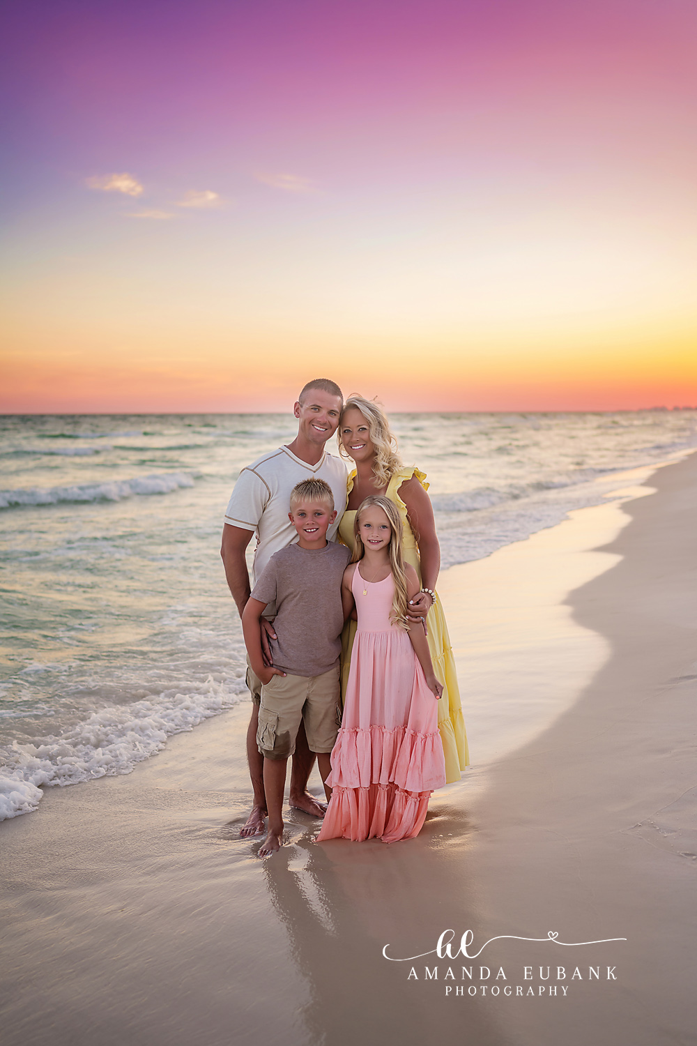 Santa Rosa Beach Family Photographer – Family of Four Pastel Sunset Portrait Family of four posed together on the beach at a soft pastel sunset, the parents with their young son and daughter, photographed by a Santa Rosa Beach family photographer
