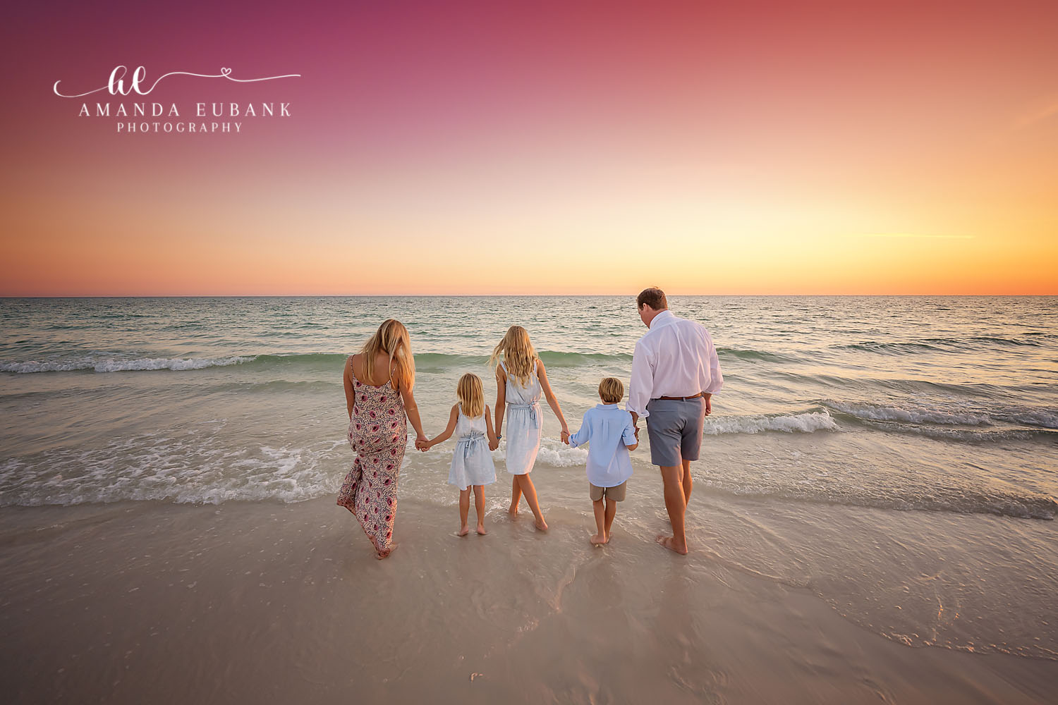Family of five walking hand in hand toward the water at sunset viewed from behind, photographed by a Santa Rosa Beach family photographer