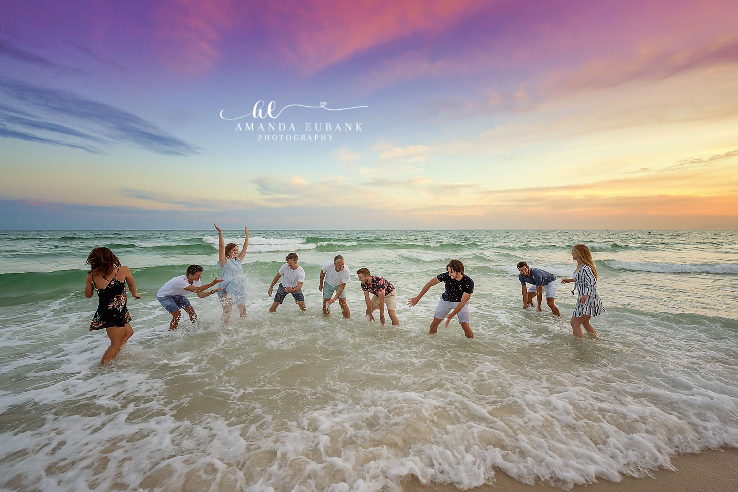 Large extended family group laughing and splashing together in the surf at sunset, photographed by a Santa Rosa Beach family photographer