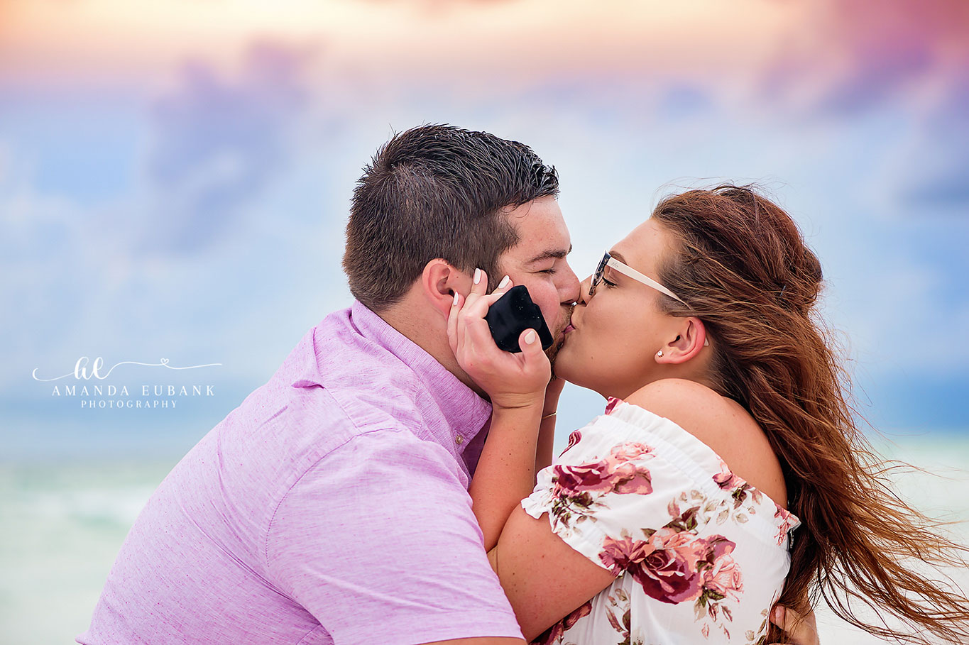 Close-up of a couple kissing on the beach, the man in a lavender shirt and the woman in a floral top, photographed by a Santa Rosa Beach engagement photographer