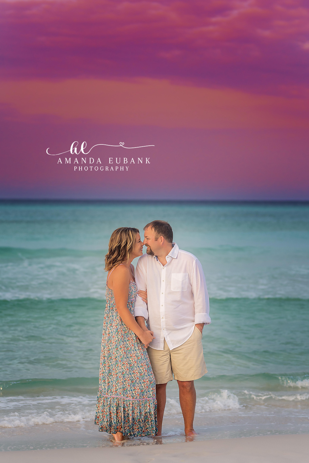 Santa Rosa Beach Engagement Photographer – Tender Couple Portrait by the Ocean Couple touching noses tenderly with the ocean and a purple sky behind them, photographed by a Santa Rosa Beach engagement photographer